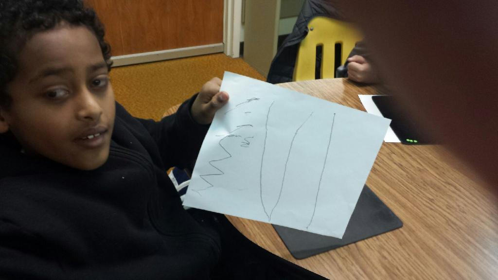 The young man holds up a picture of different kinds of lines as his first tactile drawing.